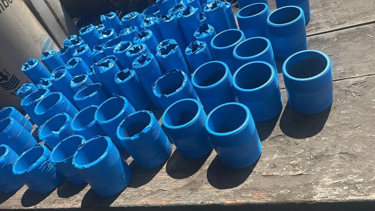 Piezas roscadas de acero recubiertas en azul sobre una mesa de madera