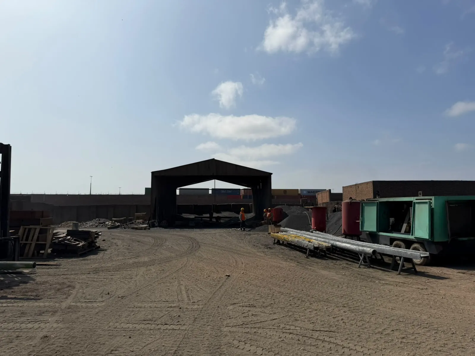 Patio de trabajo con galpón metálico, compresor y tubos de acero